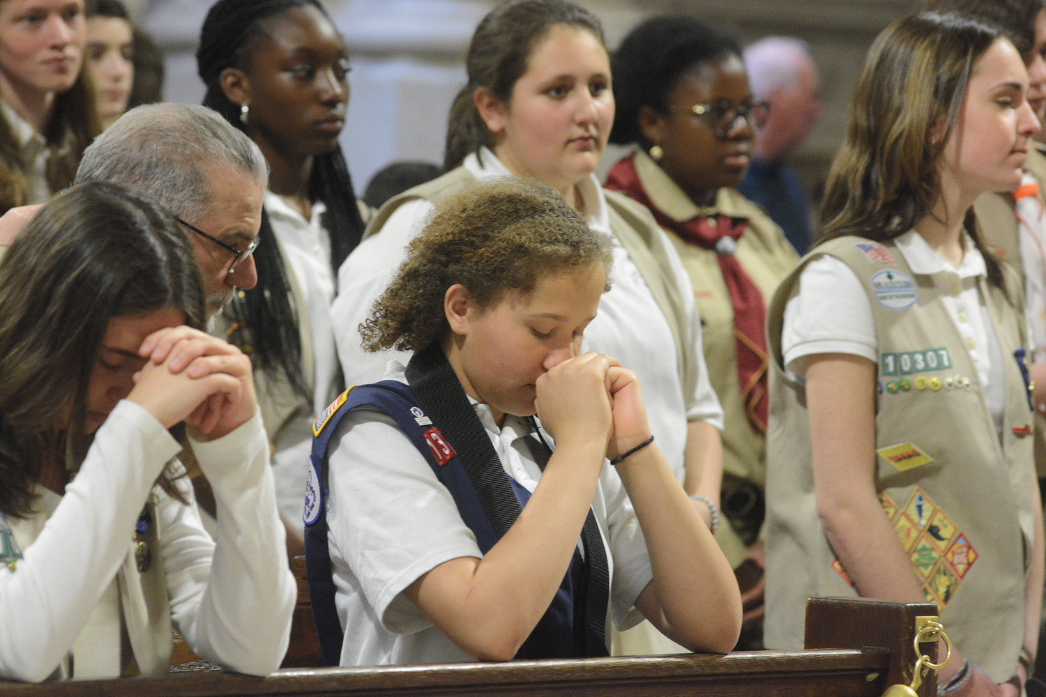 Girl Scouts kneel in prayer inside the cathedral.