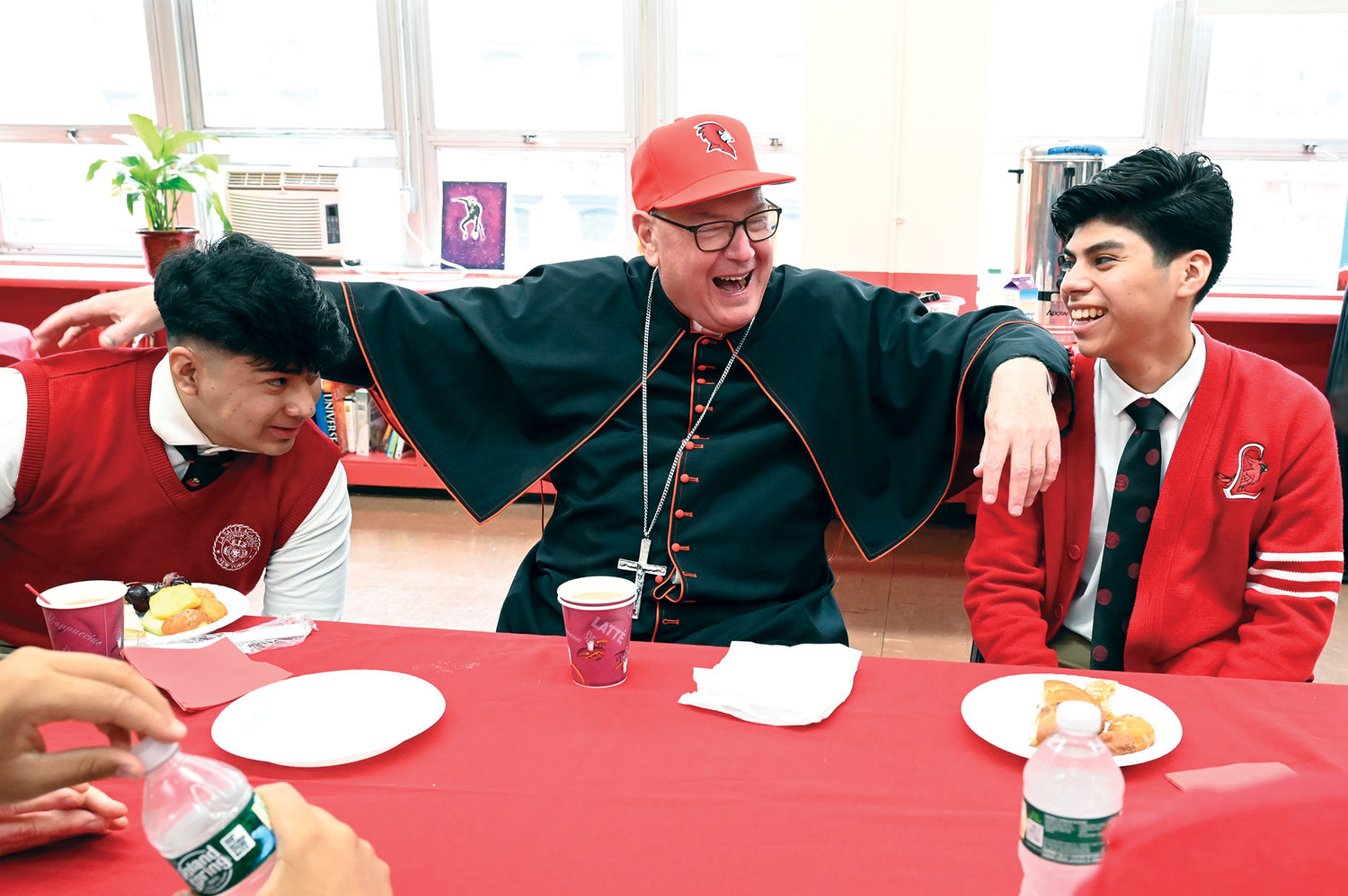 Cardinal Dolan sits down for brunch and a chat with students Giovanni Gonzalez, left, and Carlos Apreza after Mass.