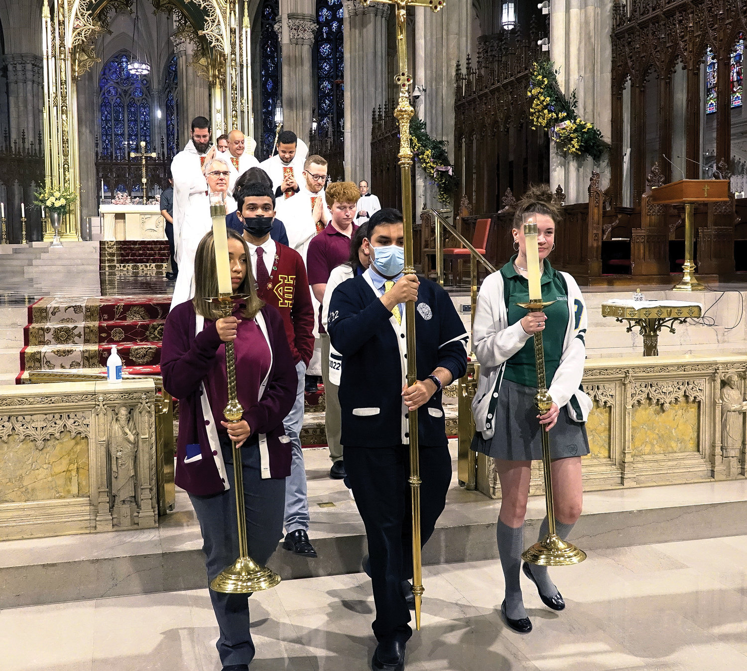 The cross bearer, flanked by candle bearers, recesses from the morning liturgy.