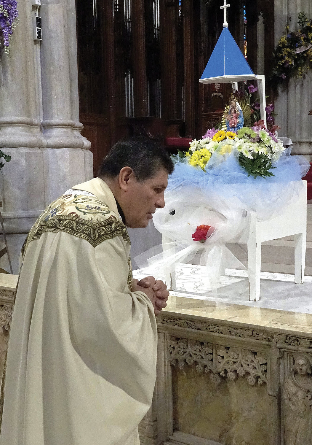 Father Lorenzo Ato, above left, prays before an image of Our Lady of Rocío before celebrating the May 29 Spanish-language Mass honoring Mary at St. Patrick’s Cathedral. Our Lady of El Rocío, whose shrine in Ecuador attracts thousands of pilgrims every year, is a Marian devotion with origins dating to 17th-century Spain.