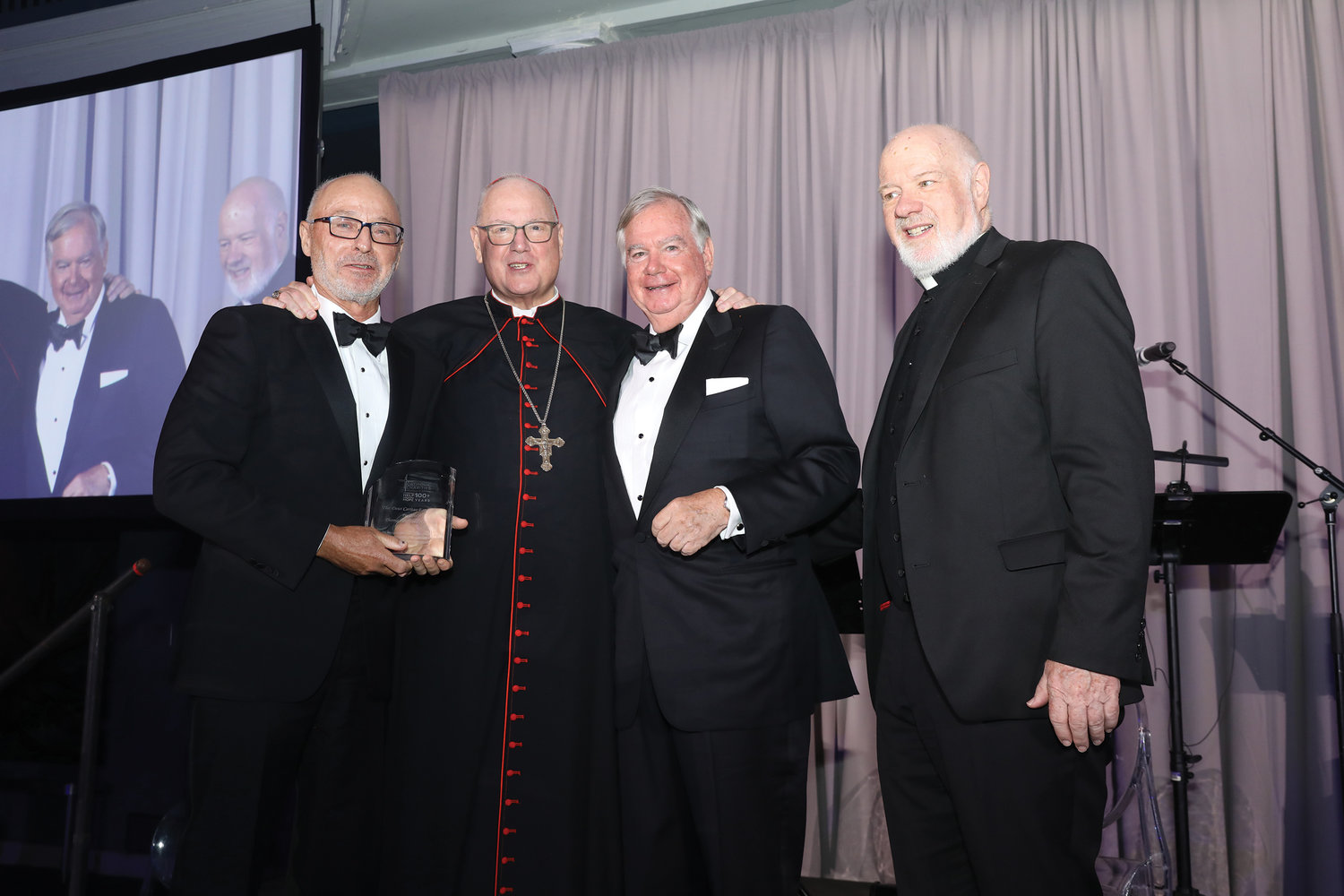 Todd Gibbons, CEO of BNY Mellon, left, receives the Deus Caritas Est Award from Cardinal Dolan, who was joined by Eugene McQuade, chair of the board of archdiocesan Catholic Charities, and Msgr. Kevin Sullivan, executive director of archdiocesan Catholic Charities.