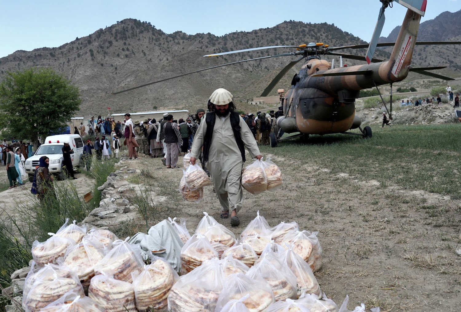 An Afghan man carries bags of bread that were transported by a Taliban helicopter June 23 to the site of a magnitude 6 earthquake the previous day in Gayan.