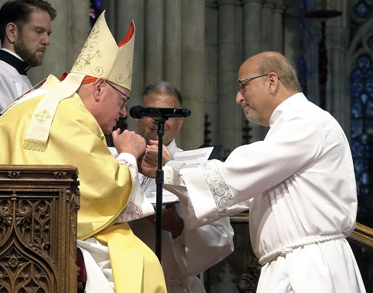 Cardinal Dolan grasps the hands of Deacon Paul Reisman during the Rite of Ordination June 18.