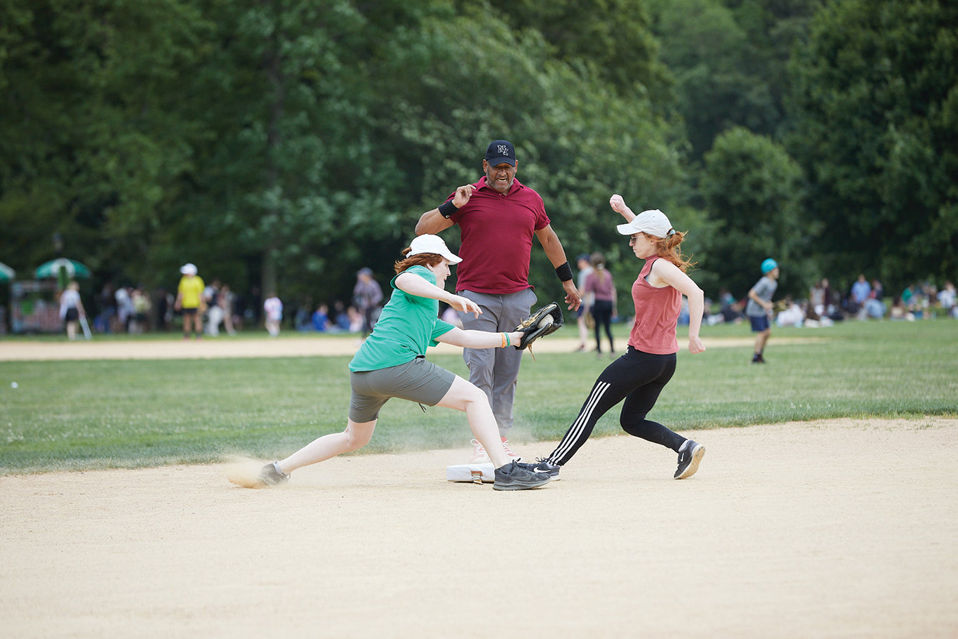 Mary Grace Lewis of the Basilica of St. Patrick’s Old Cathedral pulls into third base as Sean Halbert of St. Patrick’s Old Cathedral attempts to apply the tag during a 7-6 victory for St. Patrick’s June 18 on the Great Lawn in Central Park. Looking on is St. Patrick’s co-captain and third-base coach Omar Yapor.