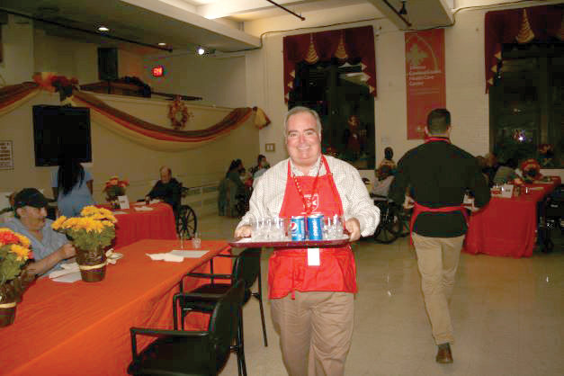 SERVING GLADLY—Fra’ John T. Dunlap smiles broadly as he totes a tray at an annual Christmas party at the Terence Cardinal Cooke Health Care Center in Manhattan, where volunteers from the Order of Malta’s American Association serve food and interact with residents.