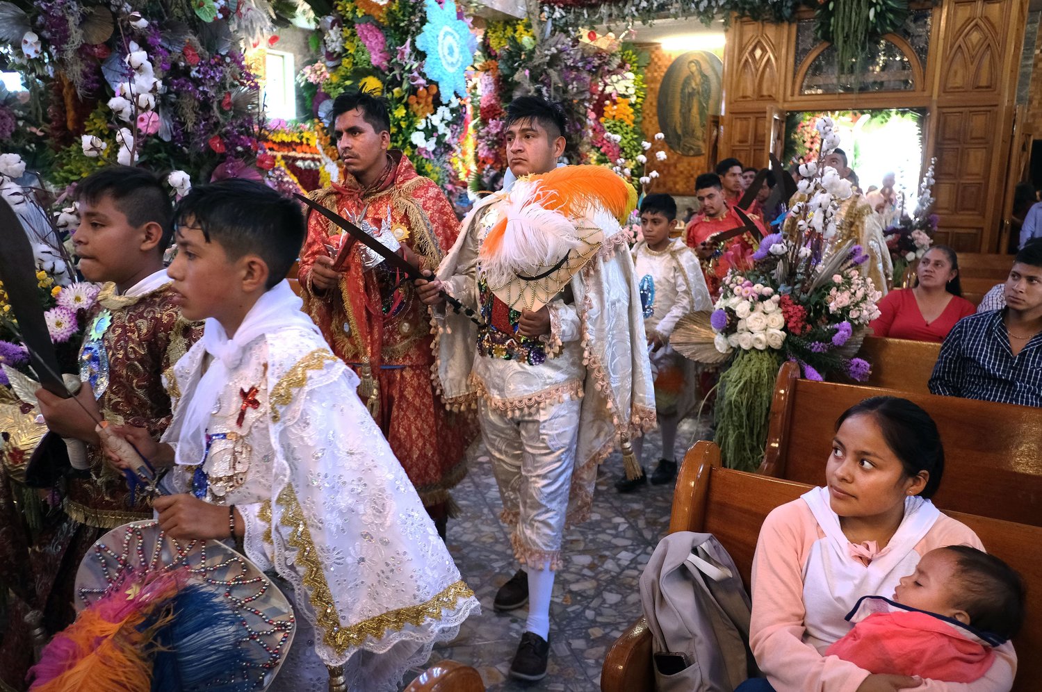 A woman watches as members of a traditional dance group enter Santa Ana Ixtlahuatzingo Catholic Church in Tenancingo, Mexico, July 26, during a celebration on the feast of the church’s patron saint, St. Anne, grandmother of Jesus.