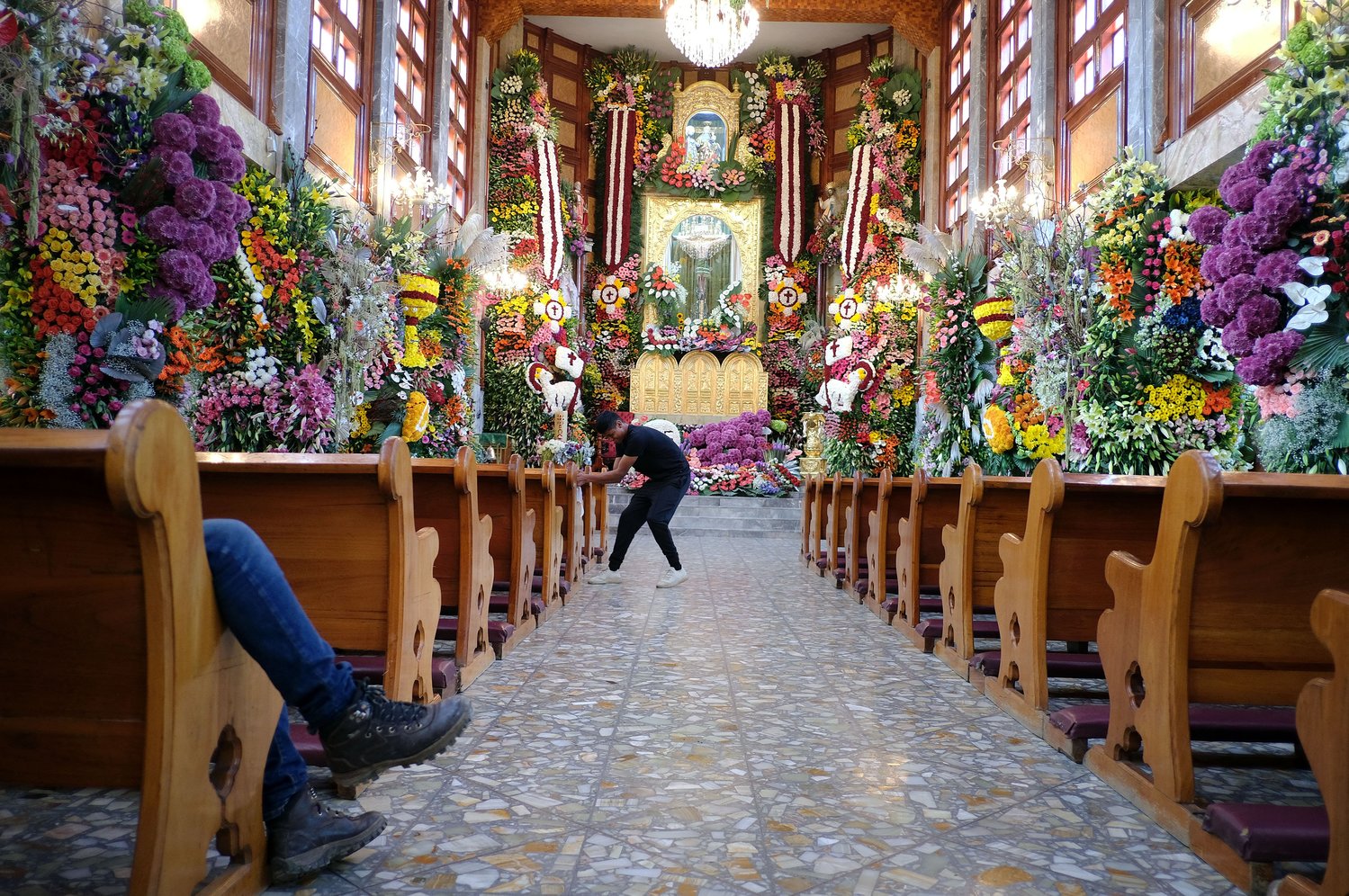 A worker makes final adjustments to a floral arrangement while another worker rests in the church pews inside Santa Ana Ixtlahuatzingo Catholic Church in Tenancingo, Mexico, July 25.