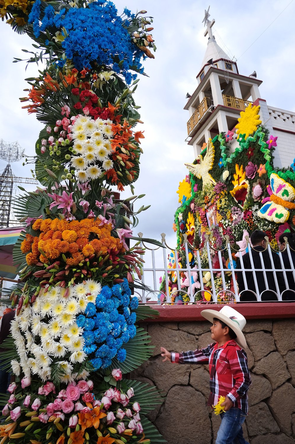 A boy reaches to touch floral arrangements outside Santa Ana Ixtlahuatzingo Catholic Church in Tenancingo, Mexico, July 26, during a celebration on the feast of the church’s patron saint, St. Anne, grandmother of Jesus.