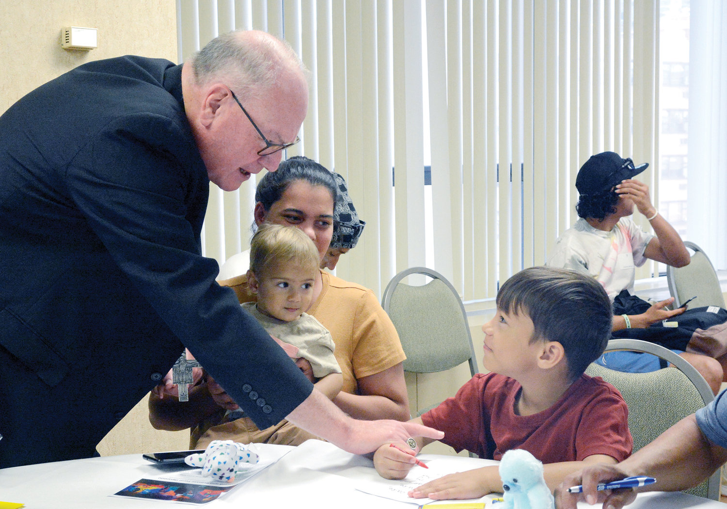 Cardinal Dolan visits with migrant families Aug. 16 inside the New York Catholic Center in Manhattan.