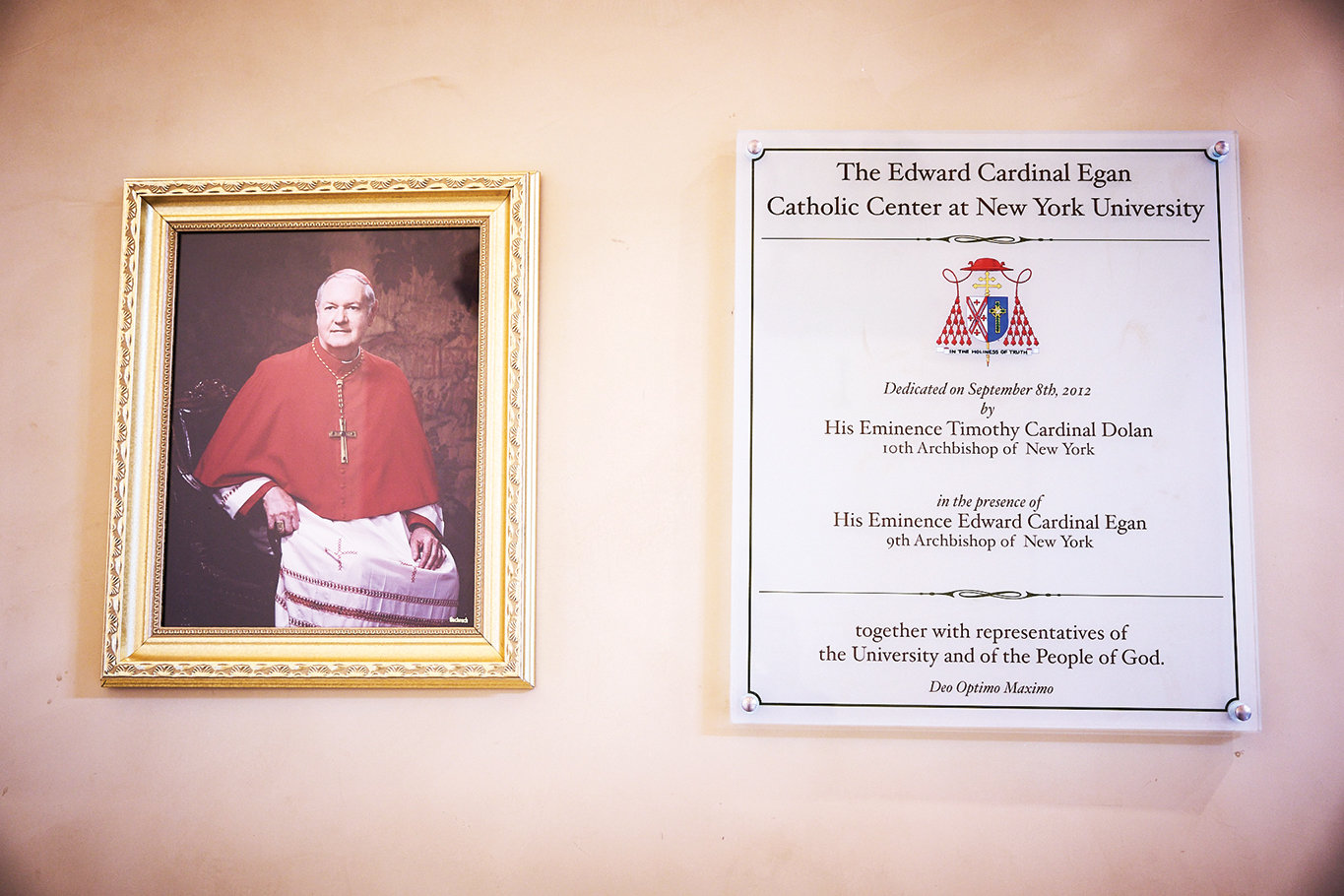 A portrait of Cardinal Egan is next to a plaque commemorating the center’s 2012 dedication.
